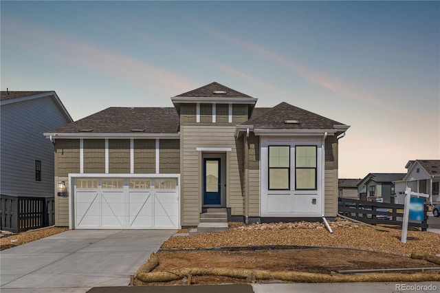 prairie-style home featuring a shingled roof, fence, entry steps, and concrete driveway