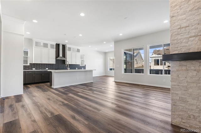 kitchen with wall chimney range hood, backsplash, white cabinets, dark wood-style floors, and recessed lighting