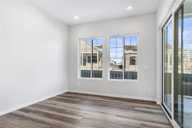 spare room with recessed lighting, baseboards, plenty of natural light, and dark wood-style flooring
