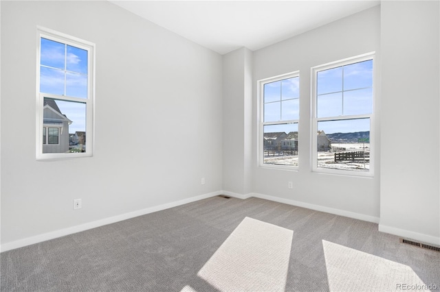 empty room with baseboards, visible vents, and carpet