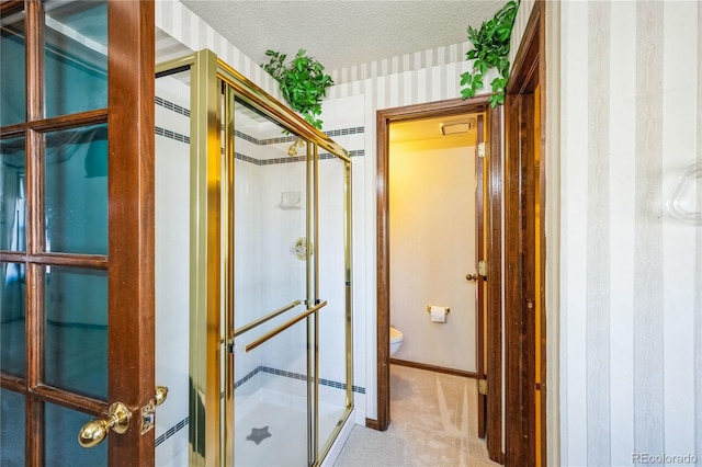 bathroom featuring toilet, a textured ceiling, and a shower with shower door