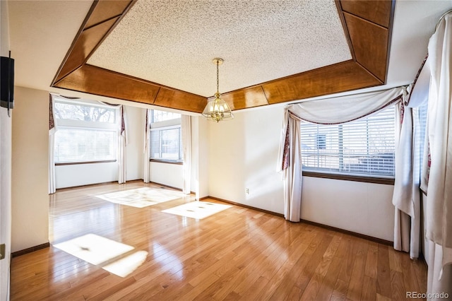 interior space featuring a notable chandelier, a textured ceiling, plenty of natural light, and wood-type flooring