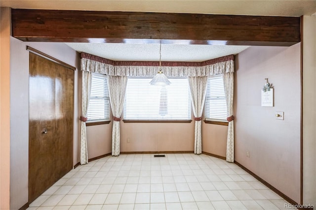 empty room with beamed ceiling and plenty of natural light