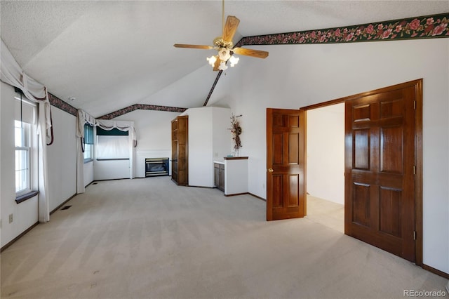 unfurnished living room featuring ceiling fan, light colored carpet, lofted ceiling, and a textured ceiling