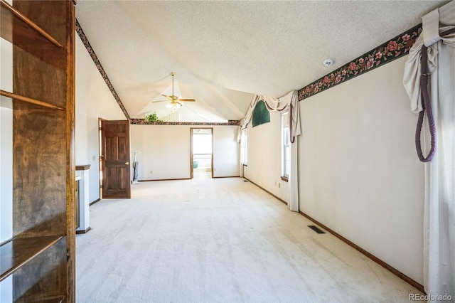 carpeted empty room with ceiling fan, lofted ceiling, and a textured ceiling