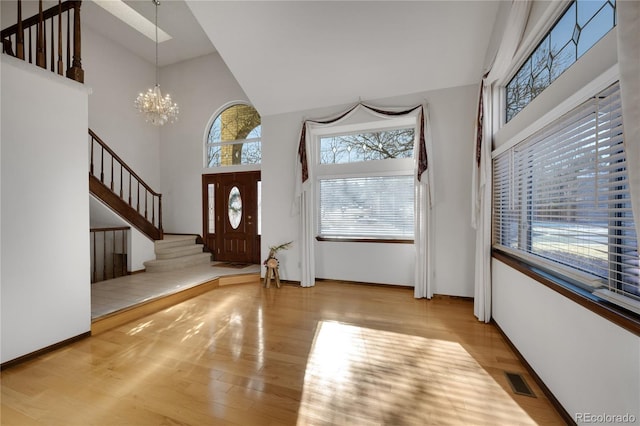 entryway featuring high vaulted ceiling, a chandelier, and light wood-type flooring