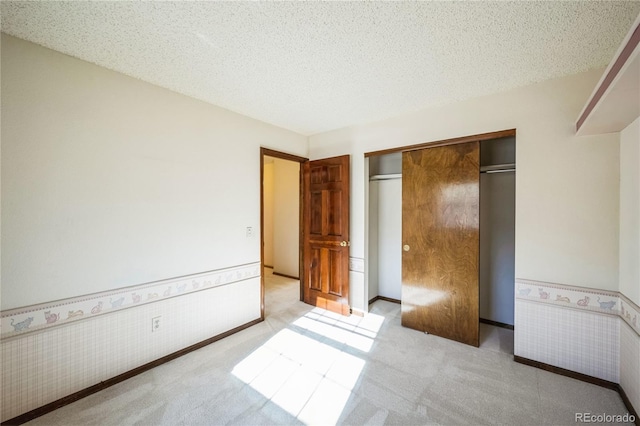 unfurnished bedroom with tile walls, a closet, a textured ceiling, and light colored carpet