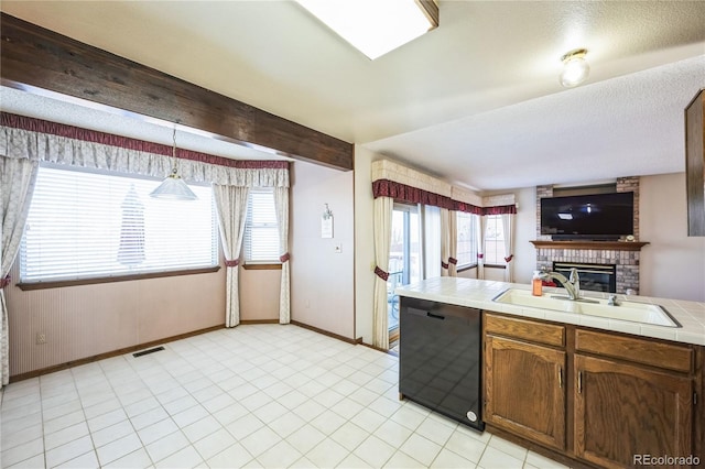 kitchen with sink, tile countertops, beamed ceiling, black dishwasher, and hanging light fixtures