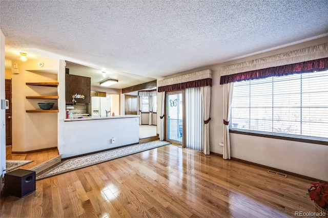 unfurnished living room featuring a textured ceiling and light hardwood / wood-style flooring