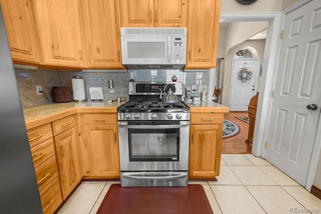 1060 Alta Vista Dr, Craig, CO 81625 - kitchen featuring white microwave, gas stove, light tile patterned flooring, and backsplash