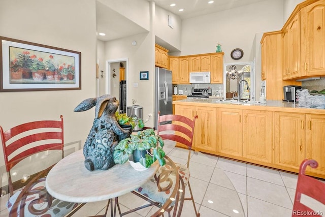 1060 Alta Vista Dr, Craig, CO 81625 - kitchen featuring stainless steel appliances, backsplash, a peninsula, light tile patterned floors, and a towering ceiling