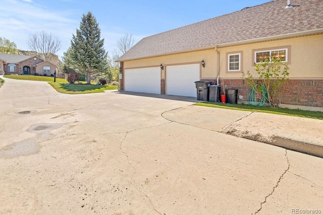 1060 Alta Vista Dr, Craig, CO 81625 - view of home's exterior with concrete driveway, brick siding, an attached garage, stucco siding, and a shingled roof