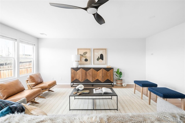 living room with baseboards, visible vents, a ceiling fan, and wood finished floors