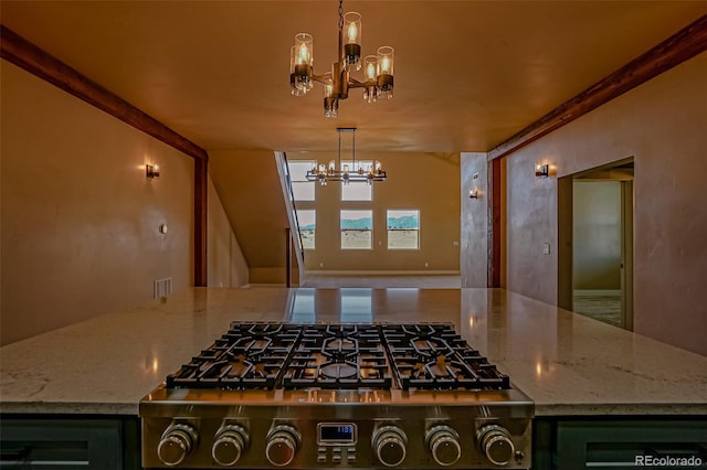 kitchen featuring stainless steel gas stovetop, decorative light fixtures, light stone counters, and ornamental molding