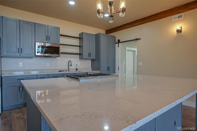 kitchen with sink, a center island, dark wood-type flooring, a barn door, and light stone counters