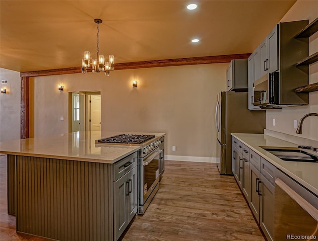 kitchen featuring appliances with stainless steel finishes, light wood-type flooring, sink, a center island, and hanging light fixtures