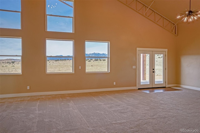 spare room featuring carpet, a mountain view, french doors, and a towering ceiling