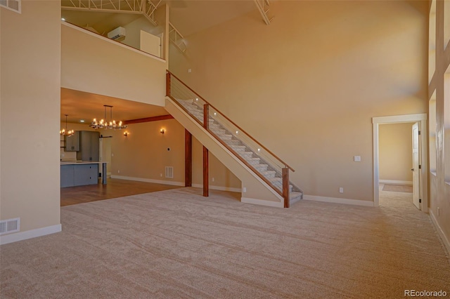 unfurnished living room featuring a towering ceiling, carpet floors, and a notable chandelier