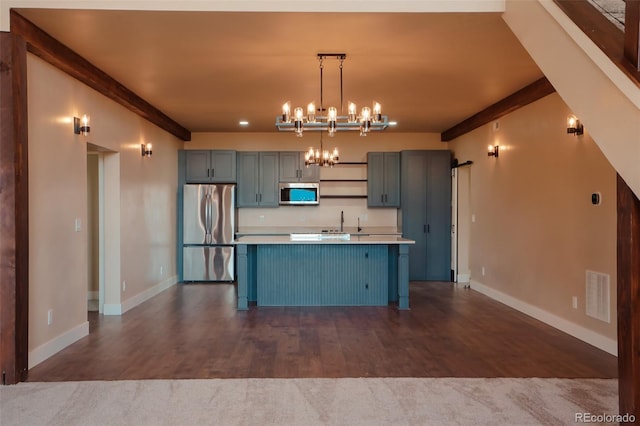 kitchen with hardwood / wood-style flooring, decorative light fixtures, an island with sink, and appliances with stainless steel finishes