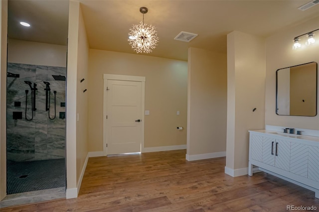 bathroom with a shower, vanity, a notable chandelier, and hardwood / wood-style flooring