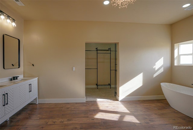 bathroom featuring wood-type flooring, vanity, and a tub to relax in