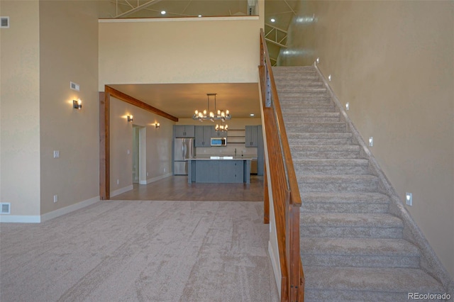 stairs with a high ceiling, carpet floors, an inviting chandelier, and crown molding