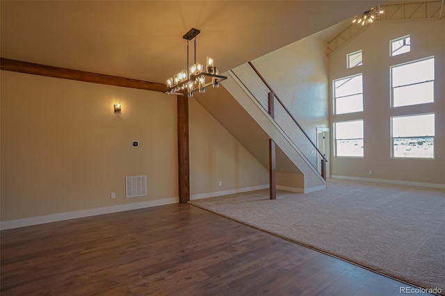 unfurnished living room featuring a chandelier, plenty of natural light, high vaulted ceiling, and wood-type flooring