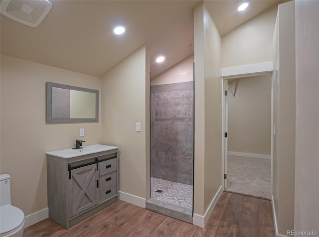 bathroom with vanity, lofted ceiling, hardwood / wood-style flooring, toilet, and walk in shower