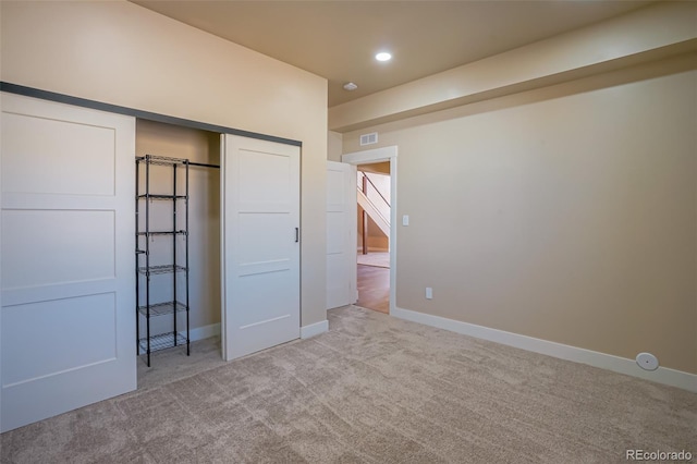 unfurnished bedroom featuring light carpet and a closet