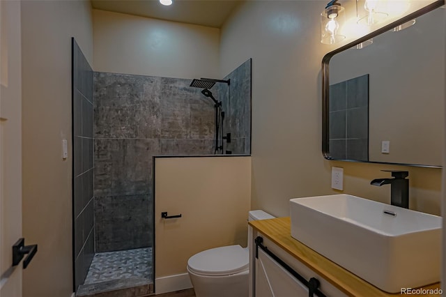 bathroom with toilet, vanity, and tiled shower