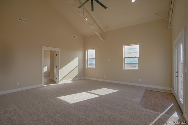 spare room with high vaulted ceiling and light colored carpet