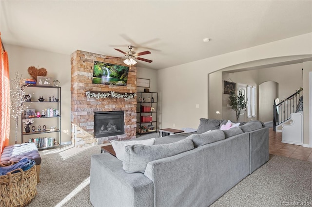 carpeted living room with ceiling fan and a fireplace