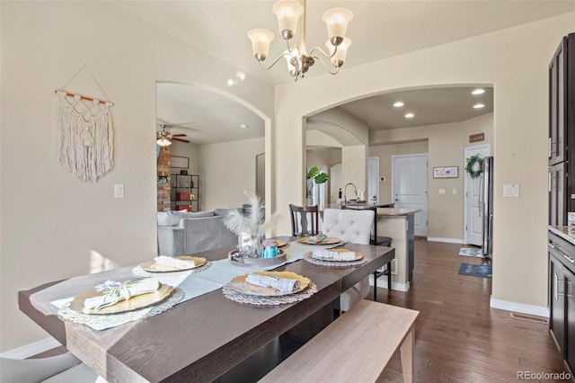 dining space with dark wood-type flooring and ceiling fan with notable chandelier