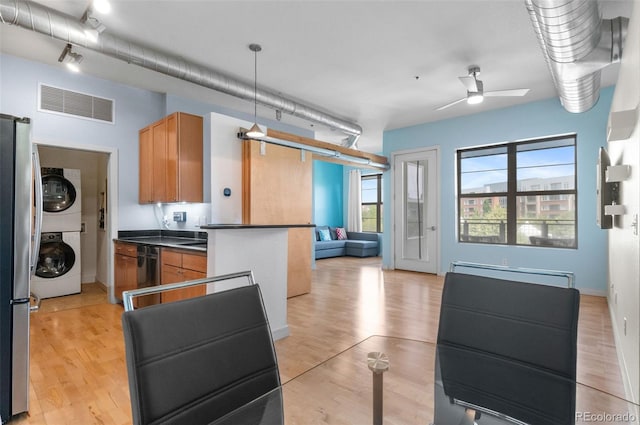 7700 E 29th Ave Unit 304, Denver, CO 80238 - kitchen with stacked washer / drying machine, dark countertops, a ceiling fan, and light wood finished floors