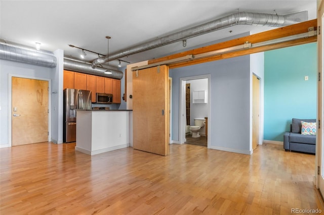7700 E 29th Ave Unit 304, Denver, CO 80238 - kitchen featuring appliances with stainless steel finishes, open floor plan, dark countertops, light wood-style flooring, and a peninsula