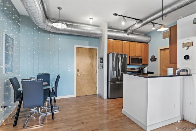 7700 E 29th Ave Unit 304, Denver, CO 80238 - kitchen featuring appliances with stainless steel finishes, light wood-type flooring, dark countertops, and brown cabinetry