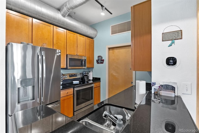 7700 E 29th Ave Unit 304, Denver, CO 80238 - kitchen with stainless steel appliances, track lighting, and brown cabinetry