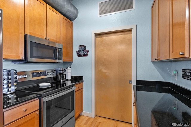 7700 E 29th Ave Unit 304, Denver, CO 80238 - kitchen featuring stainless steel appliances, light wood finished floors, and dark stone counters