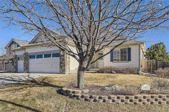 view of front of property with brick siding, a front yard, fence, a garage, and driveway