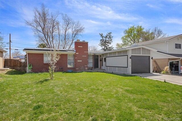 7910 Hooker St, Westminster, CO 80030 - view of front of home featuring roof mounted solar panels, fence, a front lawn, an attached garage, and concrete driveway