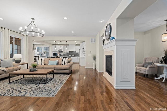 living room with a tile fireplace, dark hardwood / wood-style flooring, and a notable chandelier