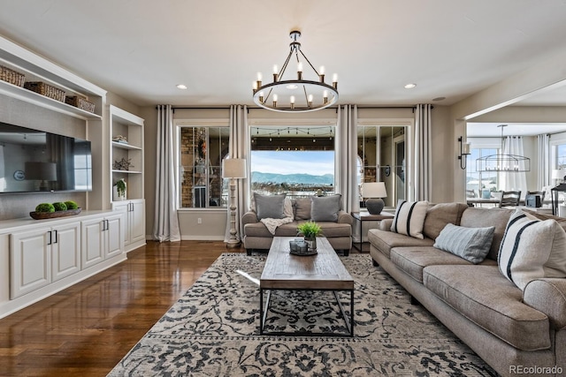 living room with built in shelves, wood finished floors, baseboards, a mountain view, and a chandelier