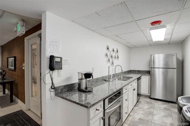 2 Adams St Unit 809, Denver, CO 80206 - kitchen with appliances with stainless steel finishes, a drop ceiling, dark stone counters, and white cabinetry
