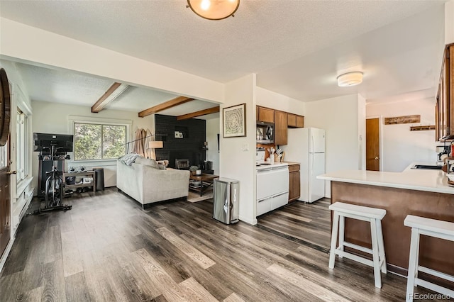 28669 Mountain View Rd, Conifer, CO 80433 - kitchen featuring range with electric stovetop, stainless steel microwave, freestanding refrigerator, dark wood-style floors, and a brick fireplace