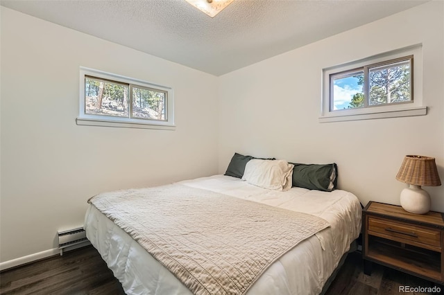 28669 Mountain View Rd, Conifer, CO 80433 - bedroom featuring multiple windows, dark wood-type flooring, baseboard heating, and a textured ceiling