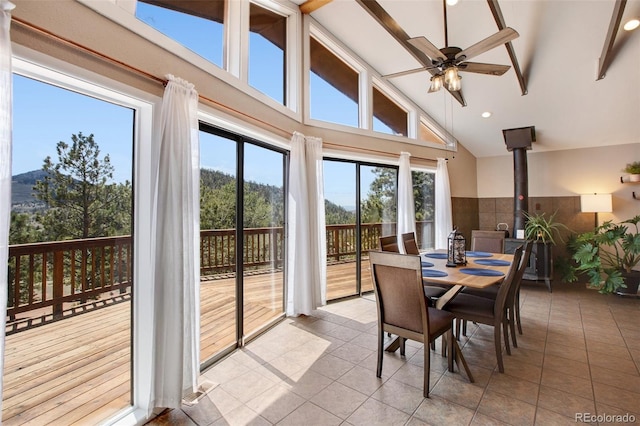 sunroom with a wood stove, lofted ceiling, and ceiling fan