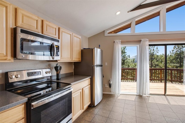 kitchen with light tile patterned floors, appliances with stainless steel finishes, vaulted ceiling, and light brown cabinets