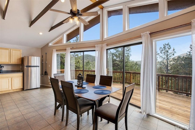 tiled dining area with a healthy amount of sunlight, beam ceiling, ceiling fan, and high vaulted ceiling