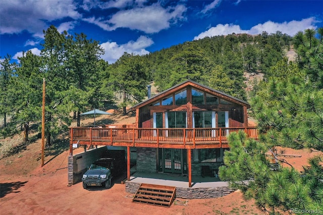 rear view of house featuring a carport and a wooden deck