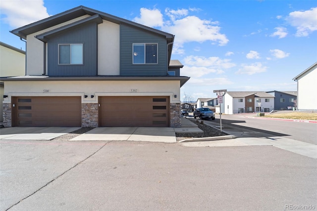 view of front of property featuring stone siding, an attached garage, and a residential view